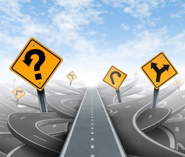 Questions and clear strategy and solutions for business leadership with a straight path to success choosing the right strategic path with yellow traffic signs cutting through a maze of tangled roads and highways.